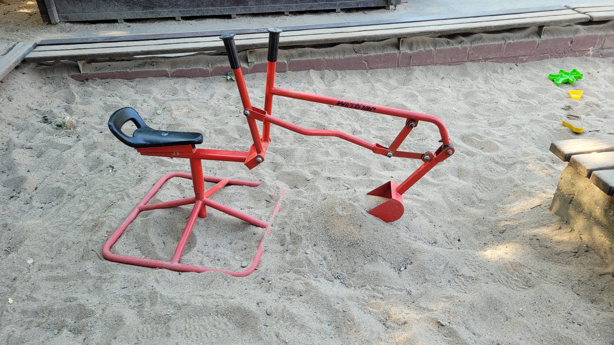 Kind spielt mit einem Sandbagger im Sandkasten